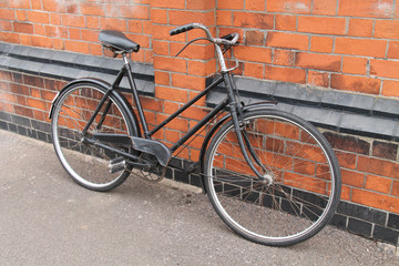 Wall Mural - A Vintage Ladies Bicycle Leaning Against a Brick Wall.