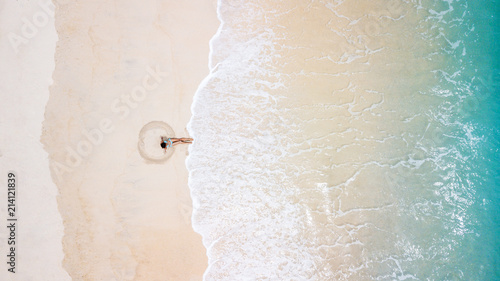 Fotografía Aerial view of young woman in blue bikini making sand angel