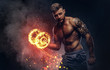 © Fxquadro - Handsome shirtless tattooed bodybuilder with stylish haircut and beard, wearing sports shorts, posing in a studio. Fire art concept.