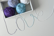 Top View Of Yarn Balls In A Wood Box. Love Word Designed From Colorful Knitting Wools Strands On White Table Background.