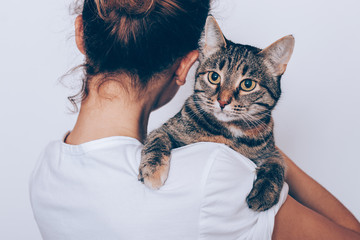 Unrecognizable young woman holding her striped cat