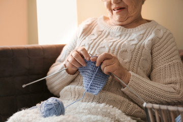 Wall Mural - Senior woman knitting warm sock at home