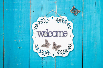 Wall Mural - Welcome sign with floral border and butterflies hanging on antique rustic teal blue wooden background