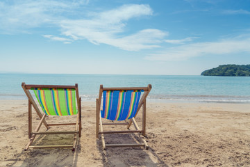 Two beach chairs on the white sand with blue sky and summer sea background. Summer, Vacation, Travel and Holiday concept.