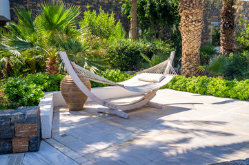 White hammock in a sunny garden with palm trees