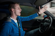 Junger männlicher Autofahrer zeigt aggressive genervte Gesten am Lenkrad
