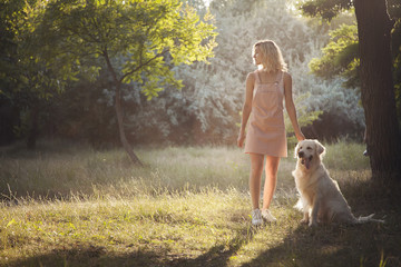 A girl and a dog are walking in the park.