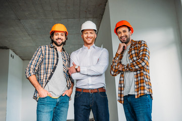 Wall Mural - group of smiling architects inside of constructing building looking at camera