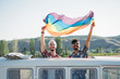 © ADDICTIVE STOCK - Smiling couple in van holding rainbow flag