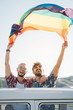 © ADDICTIVE STOCK - Gay couple in van holding LGBT flag
