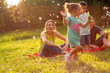 family, parenthood, adoption and people concept – Happy family with children blow soap bubbles in park.