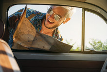 Cheerful Man With Map Looking Inside Car