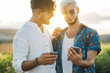 © ADDICTIVE STOCK - Cheerful gay couple using smartphones in nature