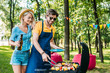 portrait of cheerful couple having barbecue in summer park