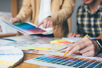 Young creative team having a meeting in creative office, Architectural drawing with work tools and accessories, Color swatch samples chart for selection coloring