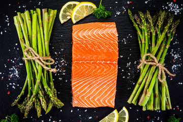 Fresh raw salmon fish served on black stone on wooden table