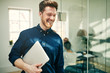 Leinwandbild Motiv Laughing young businessman walking with his laptop at work