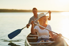 Smiling Couple Paddling Their Canoe On A Lake In Summer