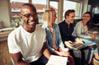 © Flamingo Images - Smiling African businessman sitting with coworkers in a modern o