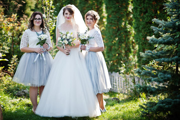 Happy bride posing with her bridesmaids outdoor with bouquets.