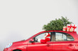 © New Africa - Authentic Santa Claus driving red car with gift boxes and Christmas tree, view from outside