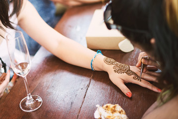 Indian henna tattoo artist drawing the uniqueness line art on the women hand