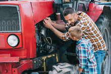 Happy Father And Son Repairing Tractor Engine Together