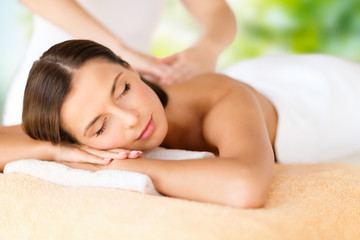 Wall Mural - wellness, spa and beauty concept - close up of beautiful woman having massage over green natural background