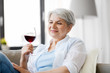 © Syda Productions - people, alcohol and leisure concept - happy smiling senior woman with glass of red wine at home