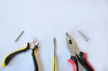 Technical items for repairing a house on a white background, screwdriver, pinchers, nails