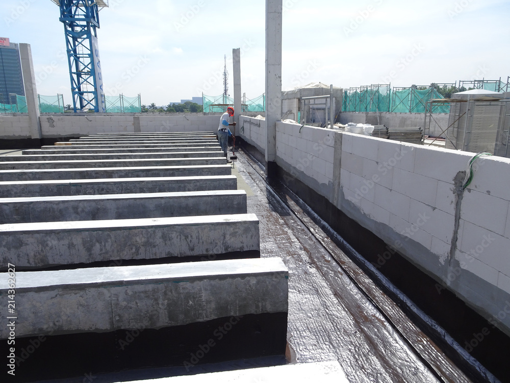 Picture of Waterproofing layer applied by construction workers on top of concrete ...