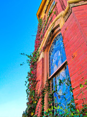 Beautiful church building in Greenville, TX, USA. Bright red brick wall of house with stained-glass windows and decor detail against blue sky.