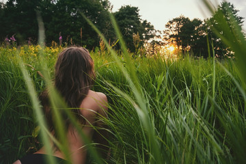 Wall Mural - young brunette woman enjoying the lying on green fresh looking on sunset.