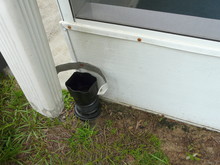 Installing Residential Downspout Connector DIY Project. A Connector Between The Downspout And Drainage Pipe Is Being Installed On A House To Seal Out Debris And Prevent Foundation Damage From Water.