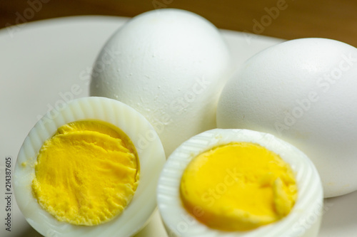 Fotografie, Obraz Hardboiled eggs with one cut in half on a plate at the kitchen table