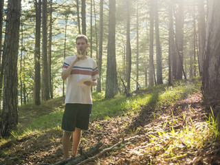 young man poet walking in the forest under the sunshine and write poetry in sketchbook