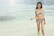 © Phawinza - Asian bikini woman with slim body swimming in blue ocean water copyspace. relaxing on beach vacation..