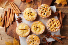 Set Of Different Mini Apple Pies Decorated Sugar Powder And Cinnamon On Wooden Table Top View. Autumn Pastry Dessert.