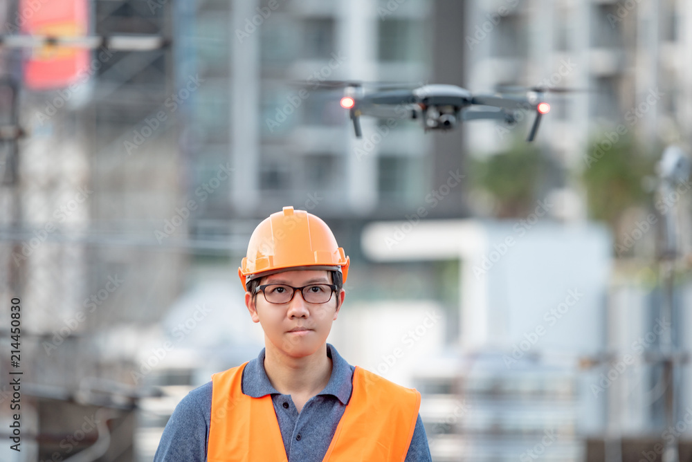 Young Asian engineer man flying drone over construction site. Using ...
