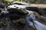 Fototapeta  - Landscape of small waterfall cascading over a rock with a long exposure