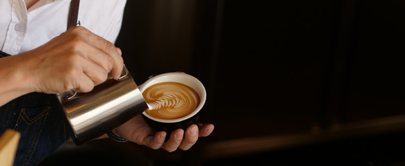 Branner of barista hand making a cup of coffee.