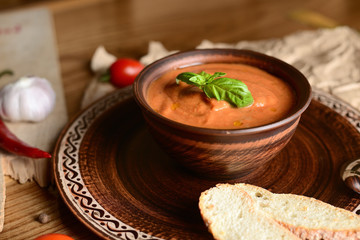 Wall Mural - tomato cream soup with basil on a wooden table