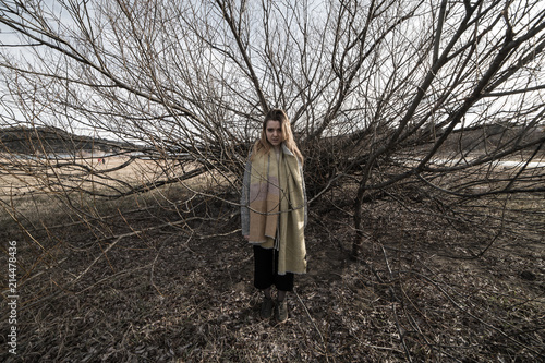 Fotografía Young woman under the dark shadow of a tree with many branches that produces a s