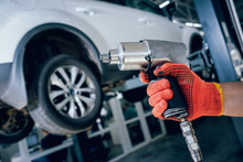 Professional Car Mechanic Working With Pneumatic Wrench In Auto Repair Service.