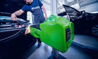 Wall Mural - Worker checks and adjusts the headlights of a car's lighting system