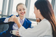 © Nattakorn - Two business woman making fits bump during talking and drinking coffee in office morning