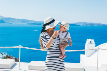 Mother and son enjoying a holiday in Santorini greece, Background the caldera and the famous Santorini volcano