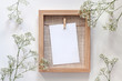 © Ester_K - A wooden frame with a white mockup card and white flowers all around