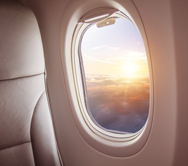 Wall Mural - airplane interior with window view of sunset above clouds.