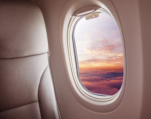 Wall Mural - airplane interior with window view of sunset above clouds.
